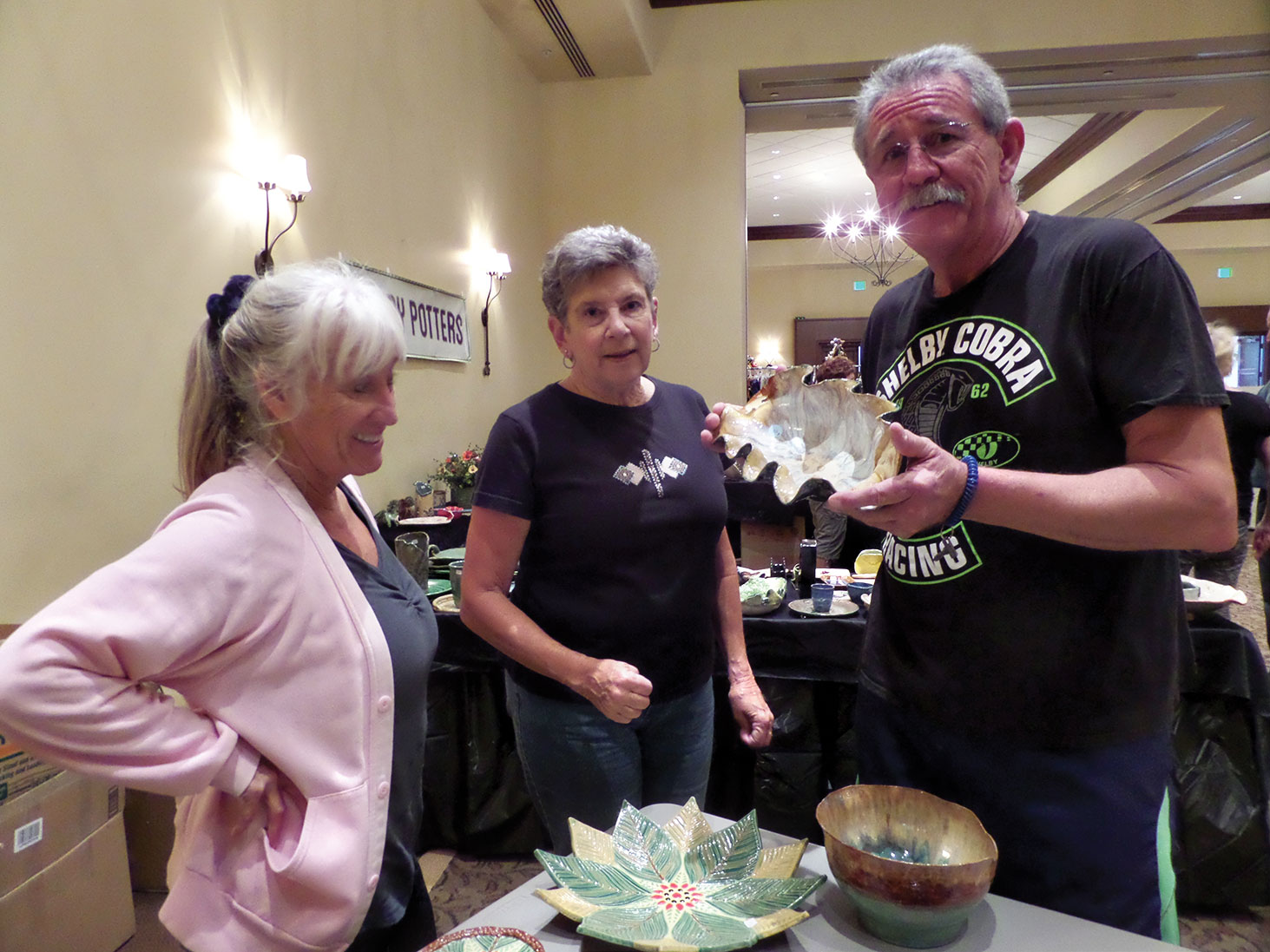Barbara Shippy, Jackie Graham and Mike Shippy look at a bowl by Liz Katz.