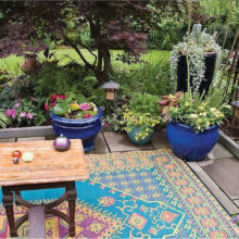 This gives you an idea of what you can do on your patio: flowers, pillows and rugs.
