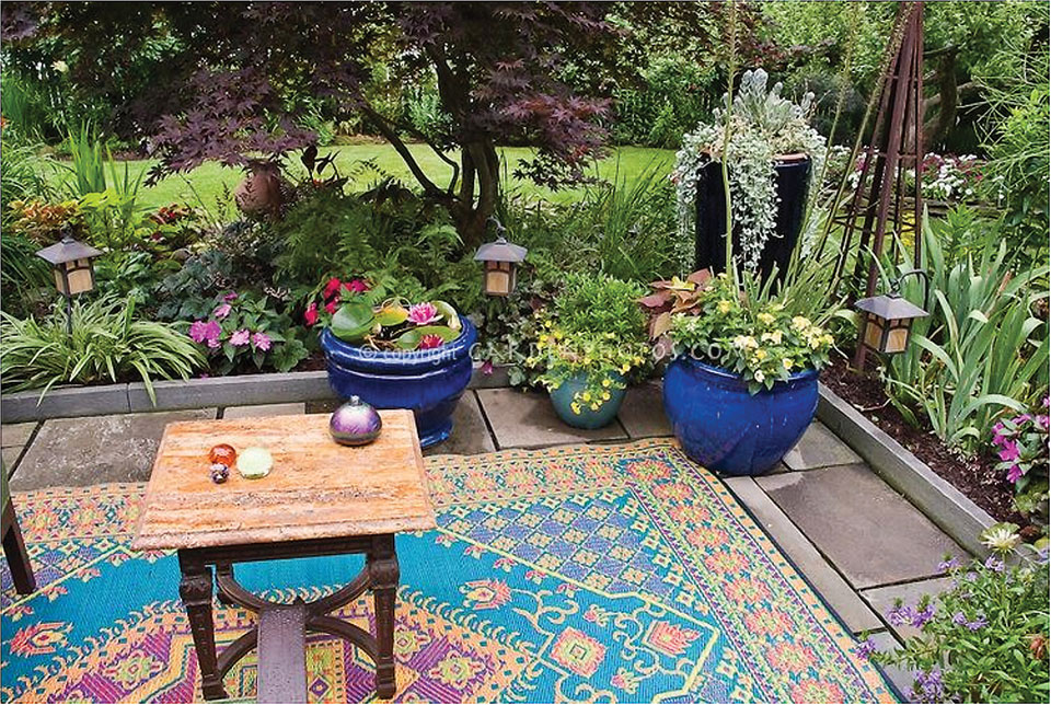 This gives you an idea of what you can do on your patio: flowers, pillows and rugs.