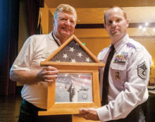 Sargent Robert Kent presents an American flag to Mike Hoernemann.