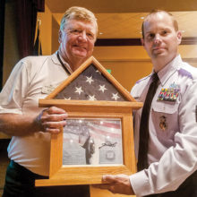 Sargent Robert Kent presents an American flag to Mike Hoernemann.