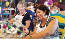 Dorothy Hogan looks on as Rosemary Simecek paints the finishing touch on her wine glass.