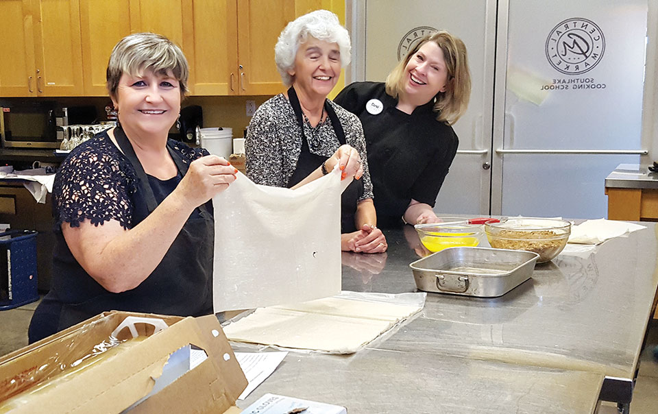 Carol Cieslik layers the phyllo for baklava while Bernadette Fidelli prepares to butter each layer while directed by a Central Market instructor.