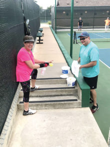Anita Freese and Tim Trotter disinfecting a pickleball after play