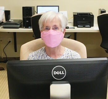 Library volunteer, Michele Nuttall, greets patrons with a smile (under her mask)!